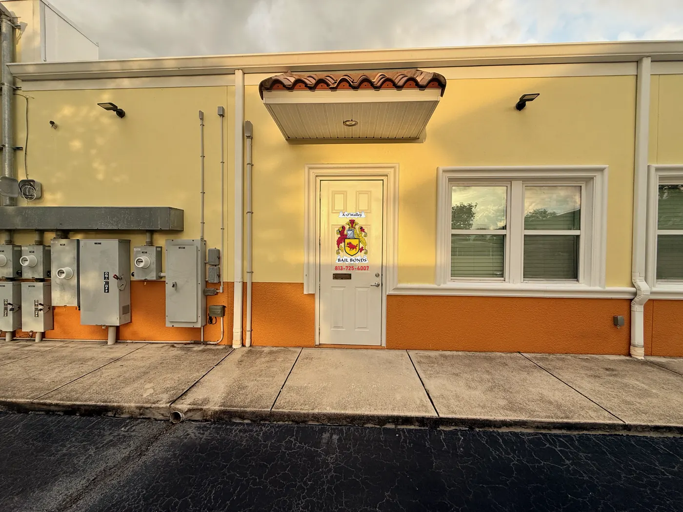 The O'Malley Bail Bonds office door, marked with the A-O'Malley crest, the words Bail Bonds and the phone number 813-725-4007, under a red tile awning