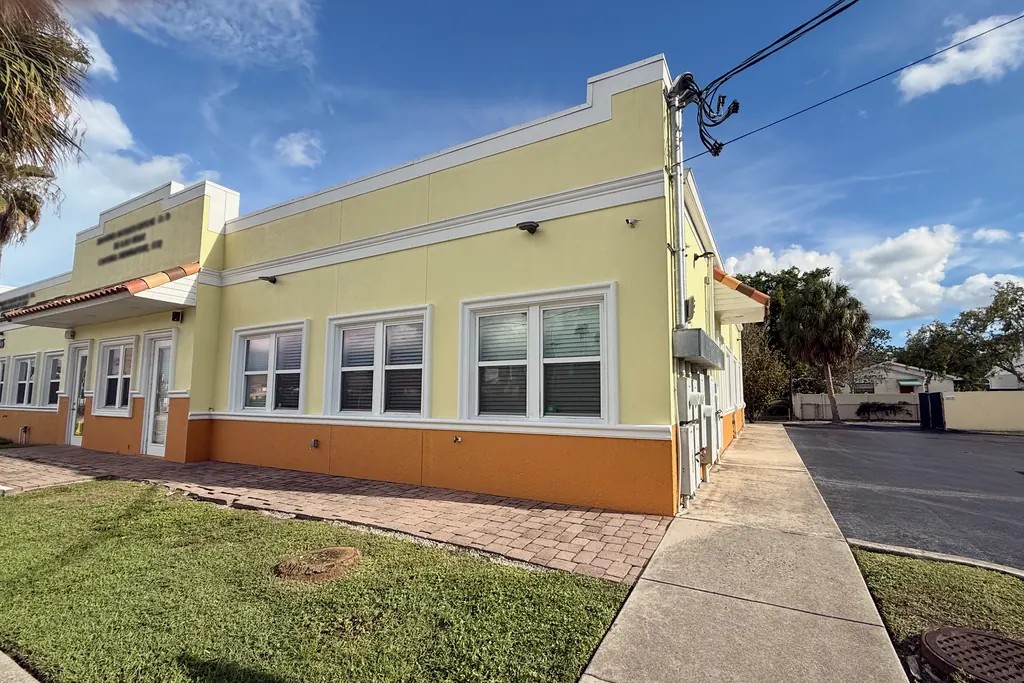 The O'Malley Bail Bonds building at 506 N Armenia Ave in Tampa, a single-story pale yellow stucco building with an orange base, white-trimmed windows and a brick paver walkway